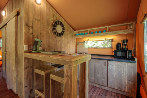 Intérieur de cuisine rustique avec meubles en bois et appareils dans la Lodgetent Brive à La Draille, France.