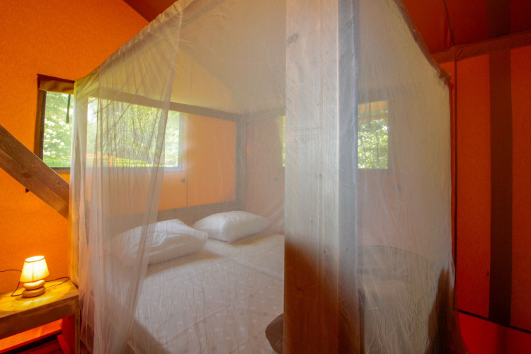 Vista del dormitorio en Lodgetent Brive en La Draille, Francia, con mosquitera y cama acogedora.