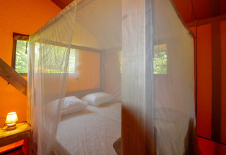 Interior bedroom view of Lodgetent Brive at La Draille in France with mosquito net and cozy bed.
