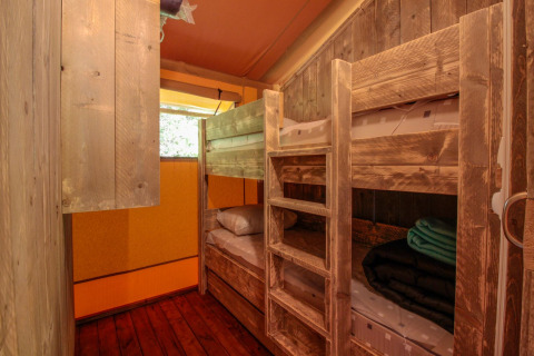 Intérieur de la Lodgetent Brive à La Draille en France, chambre rustique avec lits superposés en bois.