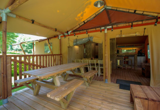 Terraza cubierta y zona de comedor en la tienda safari Lodgetent Brive en el camping La Draille en Francia.
