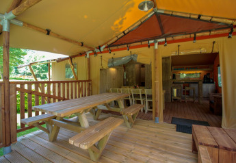 Überdachte Terrasse mit Sitzbereich im Safari-Zelt Lodgetent Brive im La Draille Camping in Frankreich.
