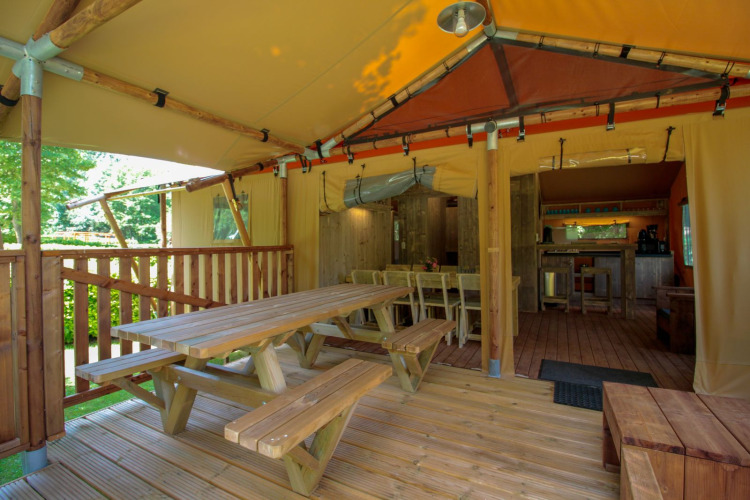 Terraza cubierta y zona de comedor en la tienda safari Lodgetent Brive en el camping La Draille en Francia.