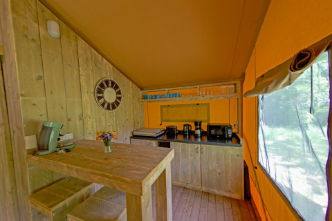 Coin cuisine du Lodgetent Brive à La Draille, France, avec mobilier en bois et équipement à café.