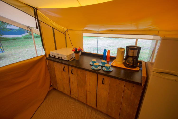 Kitchen setup inside Lodgetent St. Emilion Deluxe safari tent at La Draille, France, with appliances visible.