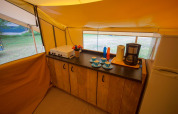 Cocina equipada en tienda safari Lodgetent St. Emilion Deluxe en La Draille, Francia, con cafetera y utensilios.