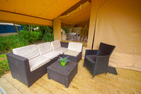 Outdoor lounge with wicker furniture on wooden deck at Lodgetent St. Emilion Deluxe, La Draille, France.