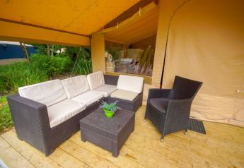 Udendørs loungeområde med fletmøbler på træterrasse i Lodgetent St. Emilion Deluxe, La Draille, Frankrig.