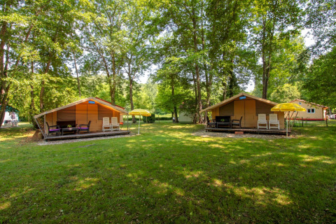 Deux tentes safari Lodgetent St. Emilion Deluxe à La Draille en France, entourées d’arbres verts et de pelouse.