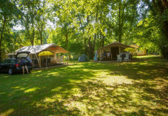 Tienda safari Lodgetent St. Emilion Deluxe en La Draille, Francia, rodeada de árboles verdes y naturaleza.