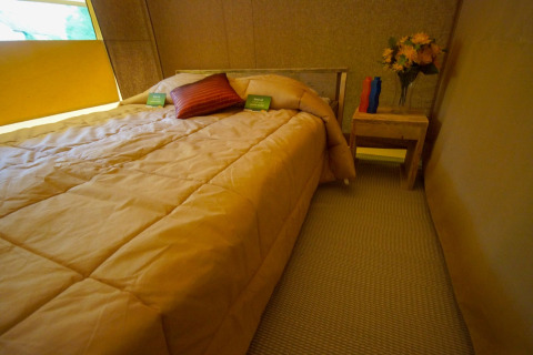 Vista interior del dormitorio en la Lodgetent St. Emilion Deluxe en La Draille, Francia, con una cama doble.