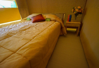 Interieur van de slaapkamer in Lodgetent St. Emilion Deluxe bij La Draille, Frankrijk, met tweepersoonsbed.