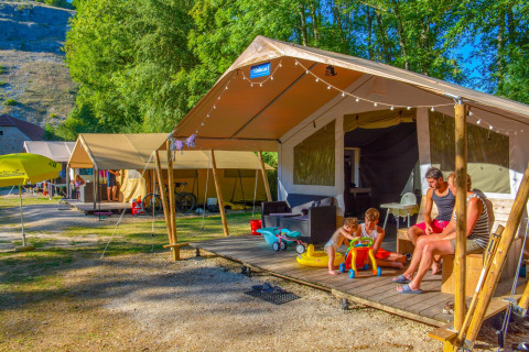 Eine Familie entspannt vor einem Safari-Zelt der Lodgetent St. Emilion Deluxe in La Draille, Frankreich.