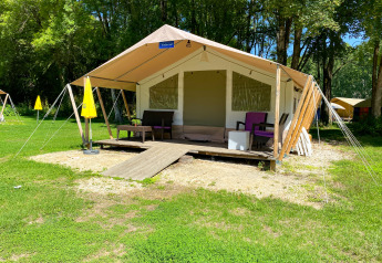 Safari tent Lodgetent St. Emilion Deluxe at La Draille in France, featuring porch seating and lush greenery.
