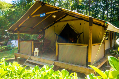Tienda safari Lodgetent Gourdon en La Draille, Francia, con terraza de madera, muebles y vegetación.