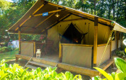 Tienda safari Lodgetent Gourdon en La Draille, Francia, con terraza de madera, muebles y vegetación.