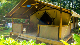 Tienda safari Lodgetent Gourdon en La Draille, Francia, con terraza de madera, muebles y vegetación.