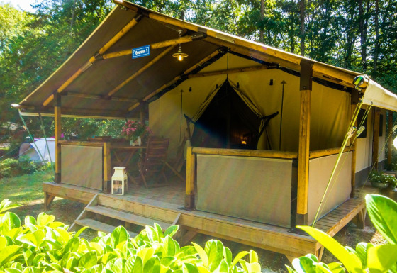 Safari tent Lodgetent Gourdon at La Draille in France, featuring a wooden deck, furniture, and lush greenery.