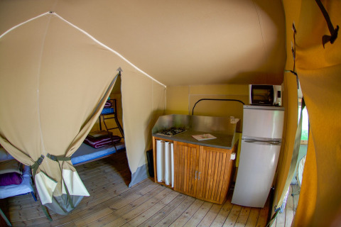 Intérieur d'une tente safari Lodgetent Gourdon à La Draille en France, avec cuisine et lits superposés.