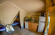 Innenansicht eines Lodgetent Gourdon Safari-Zeltes in La Draille, Frankreich, mit Küche und Betten.