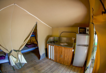 Innenansicht eines Lodgetent Gourdon Safari-Zeltes in La Draille, Frankreich, mit Küche und Betten.