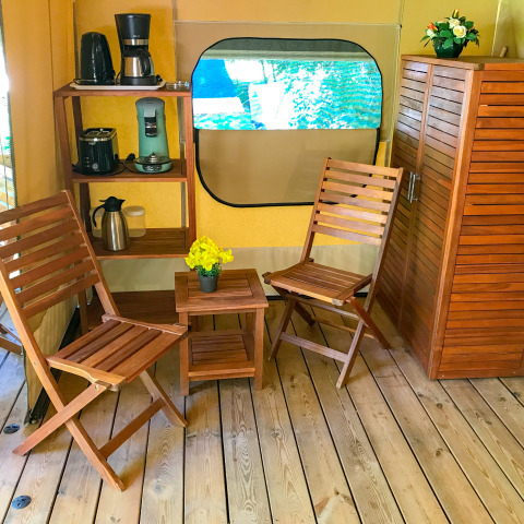 Interior de la tienda safari Lodgetent Gourdon en La Draille, Francia, con muebles de madera y cafetera.