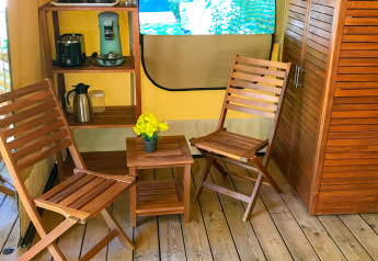 Innenraum des Safari-Zelts Lodgetent Gourdon in La Draille, Frankreich, mit Holzmöbeln und Kaffeemaschine.