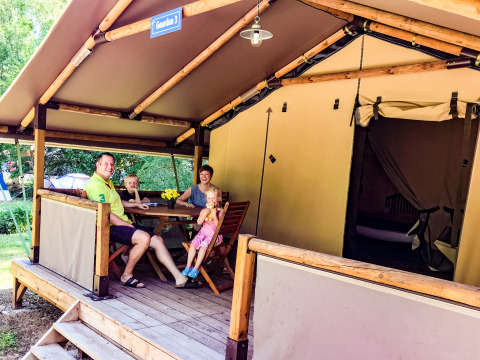 Une famille profite de la terrasse devant une tente safari Lodgetent Gourdon à La Draille, en France.
