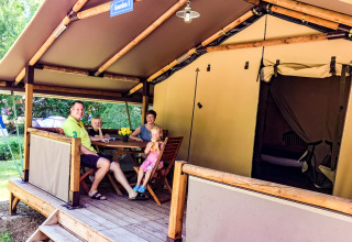 Een gezin zit gezellig buiten bij Lodgetent Gourdon op La Draille in Frankrijk aan een houten tafel.