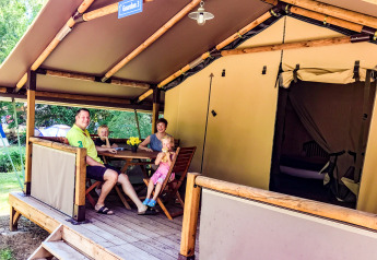 Een familie geniet op het terras voor een Lodgetent Gourdon-safaritent bij La Draille, Frankrijk.