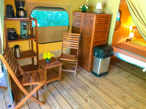 Interieur van safaritent Lodgetent Gourdon bij La Draille, Frankrijk, met houten meubels en apparatuur.