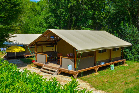 Tienda de safari Lodgetent Gourdon en La Draille, Francia, rodeada de vegetación y luz solar de verano.