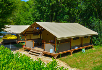 Tienda de safari Lodgetent Gourdon en La Draille, Francia, rodeada de vegetación y luz solar de verano.