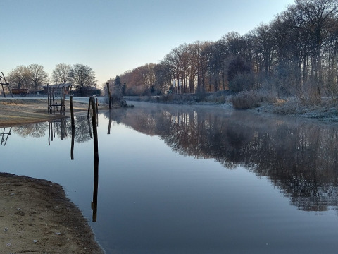 Vue de la rivière à la River Lodge, Camping de Koeksebelt, Pays-Bas, avec arbres givrés et eau réfléchissante.