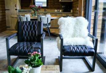 Interieur van River Lodge bij Camping de Koeksebelt met leren stoelen, schapenvacht en houten accenten.