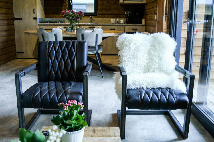 Innenraum der River Lodge im Camping de Koeksebelt mit Ledersesseln, Fell und moderner Holzeinrichtung.