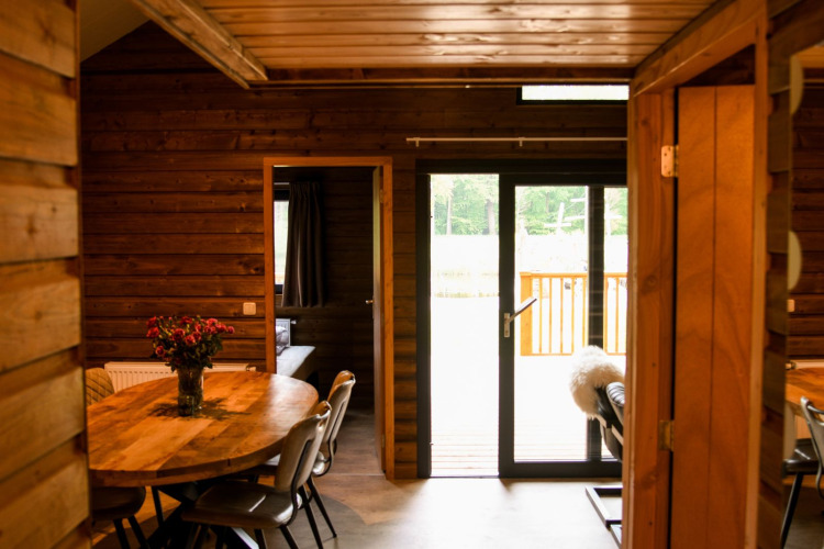 Innenaufnahme der River Lodge auf Camping de Koeksebelt in den Niederlanden mit Holzwänden und Esstisch.