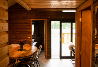 Vista interior de River Lodge en Camping de Koeksebelt, Países Bajos, con paredes de madera y mesa de comedor.