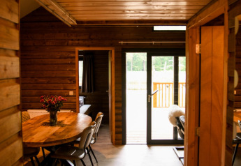 Vista interior de River Lodge en Camping de Koeksebelt, Países Bajos, con paredes de madera y mesa de comedor.