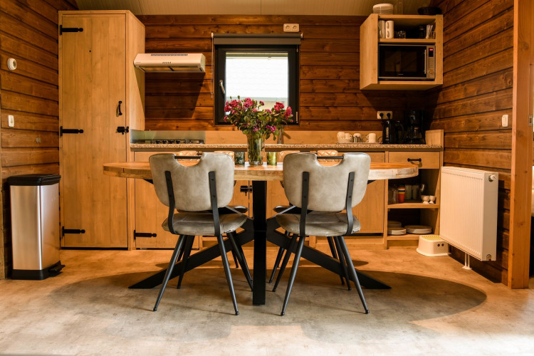 Gemütliche Küchenzeile in der River Lodge bei Camping de Koeksebelt, Niederlande, mit Holzwänden und Tisch.