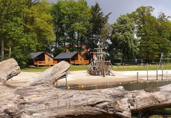 Photo de River Lodge au Camping de Koeksebelt aux Pays-Bas, avec cabanes en bois, plage et aire de jeux.