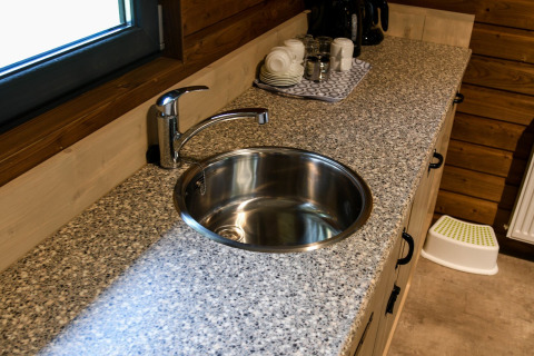 Round sink in granite countertop at River Lodge, Camping de Koeksebelt, Netherlands, cups in the background.
