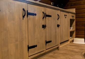 Wooden cabinets with black handles and latches in River Lodge at Camping de Koeksebelt, Netherlands.