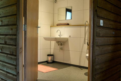 Baño accesible en River Lodge del Camping de Koeksebelt, Países Bajos, con lavabo y espejo instalados.