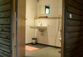 Salle de bain accessible à la River Lodge du Camping de Koeksebelt, Pays-Bas, avec lavabo et miroir.