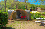 Tienda safari Le Petit Chateau en La Draille, Francia, con dos sillas rojas y mesa de picnic afuera.