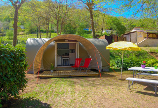 Tienda safari Le Petit Chateau en La Draille, Francia, con dos sillas rojas y mesa de picnic afuera.