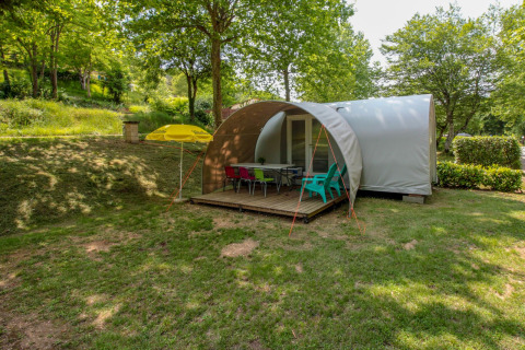 Tienda safari Le Petit Chateau en La Draille, Francia, rodeada de árboles y mobiliario exterior.