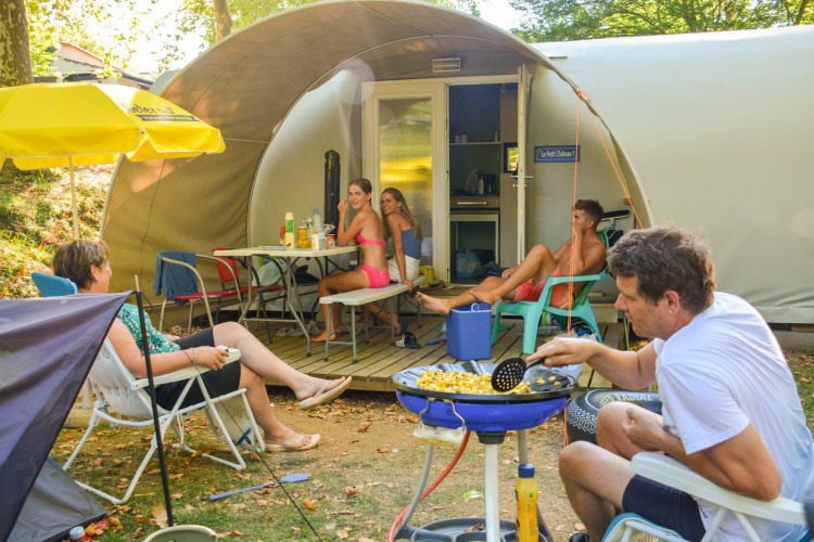 Familia disfrutando y cocinando frente a la tienda safari Le Petit Chateau en La Draille, Francia.