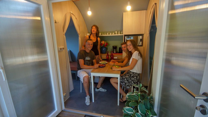 Vier Personen sitzen gemeinsam in einem Safari-Zelt Le Petit Chateau bei La Draille, Frankreich, beim Essen.